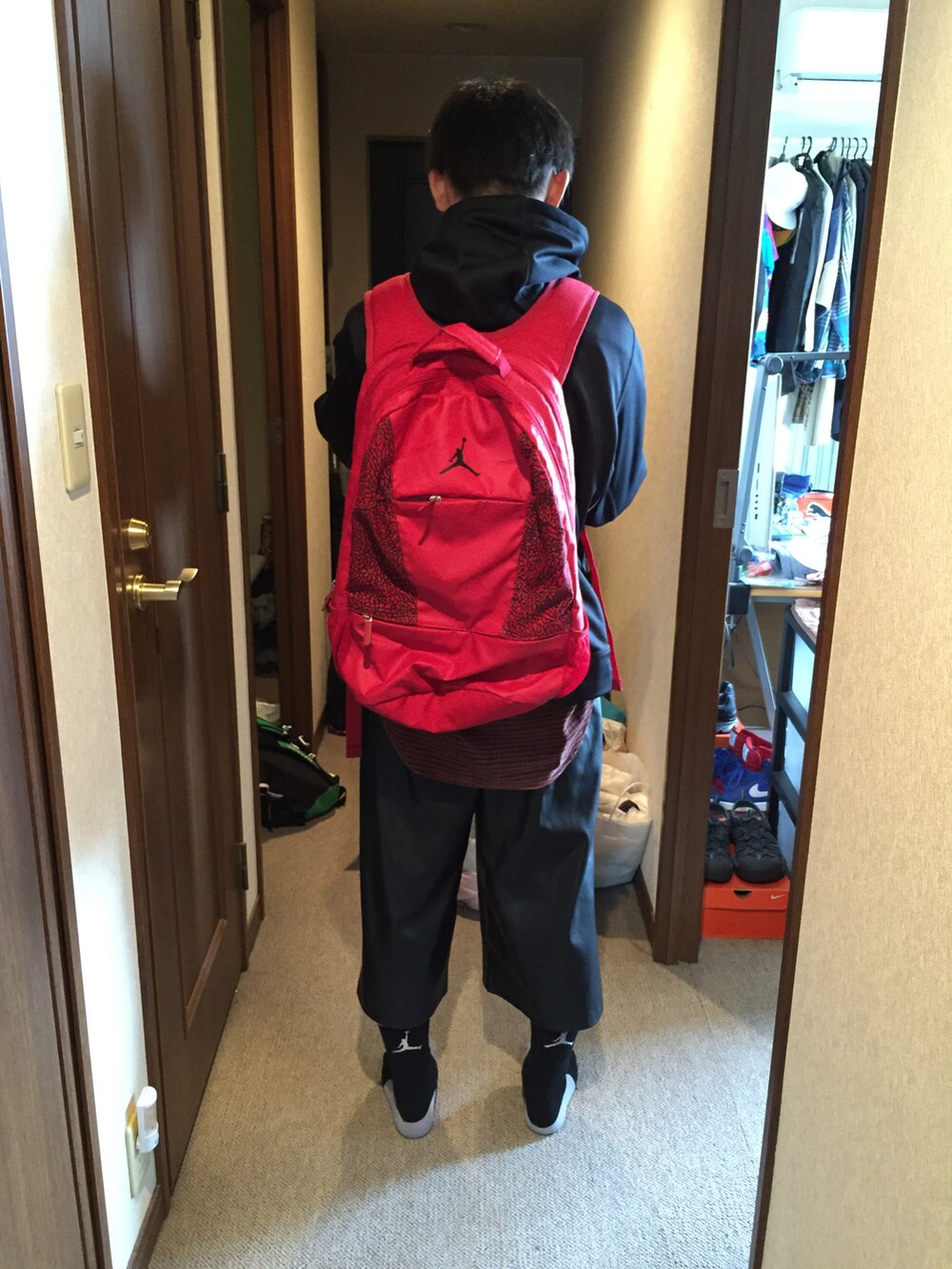 ブラック系のパーカー、ブラック系のその他パンツ、レッド系のバックパック/リュックを着用したメンズの夏コーディネートの2枚目の写真