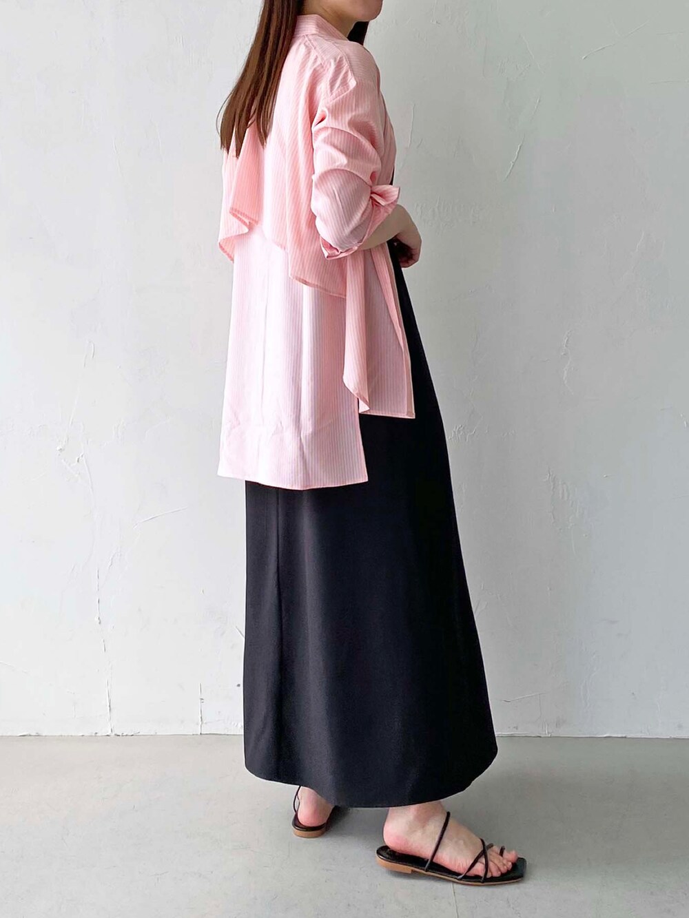 ピンク系のシャツ/ブラウス、ブラック系のワンピース、ゴールド系のネックレスを着用したレディースの春コーディネートの2枚目の写真