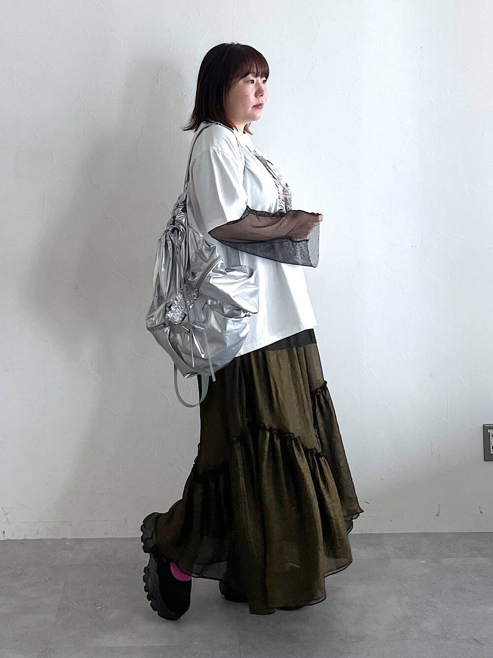 シルバー系のショルダーバッグ、ブラック系のスカート、ホワイト系のTシャツ/カットソーを着用したレディースの春コーディネートの2枚目の写真