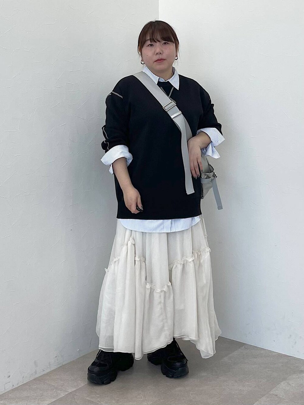 シルバー系のショルダーバッグ、ブルー系のシャツ/ブラウス、ブラック系のニット/セーターを着用したレディースの冬コーディネートの2枚目の写真