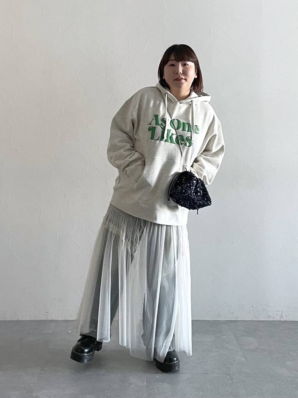 ブルー系のデニムパンツ、ホワイト系のスカート、ブラック系のショルダーバッグを着用したレディースの秋コーディネートの4枚目の写真