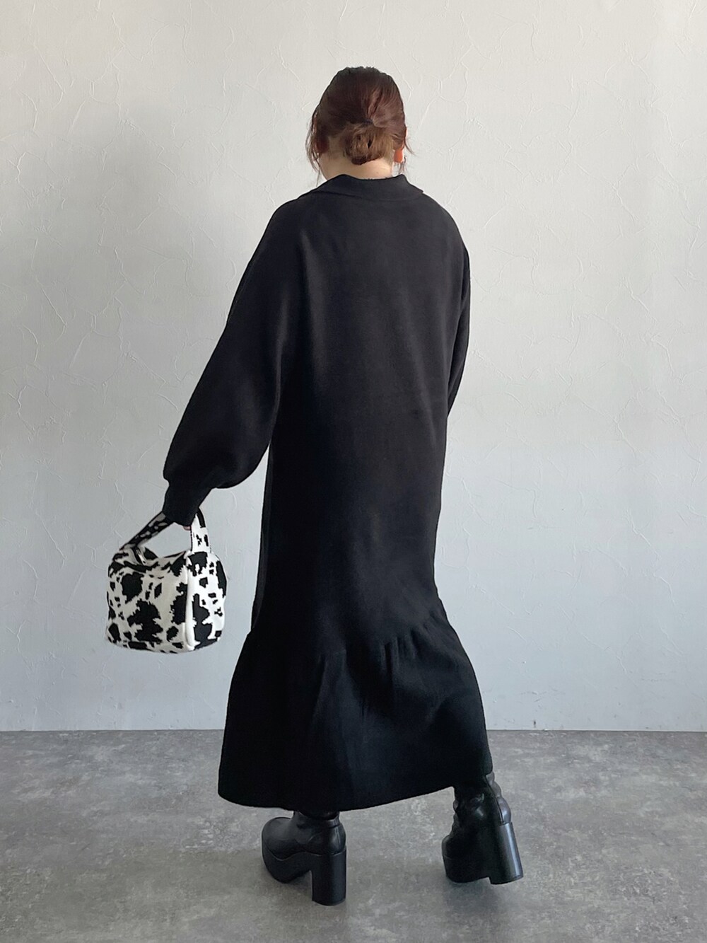 ブラック系のハンドバッグ、ブラック系のワンピース、ブラック系のブーツを着用したレディースの秋コーディネートの3枚目の写真