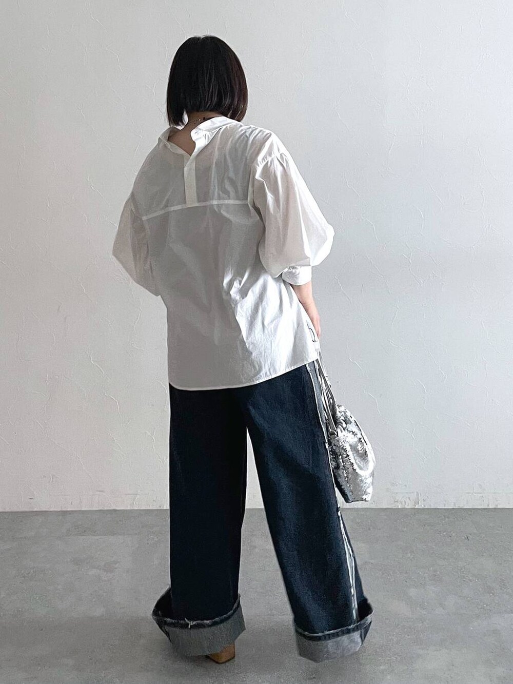 シルバー系のショルダーバッグ、ブルー系のデニムパンツ、ブラック系のローファーを着用したレディースの秋コーディネートの2枚目の写真