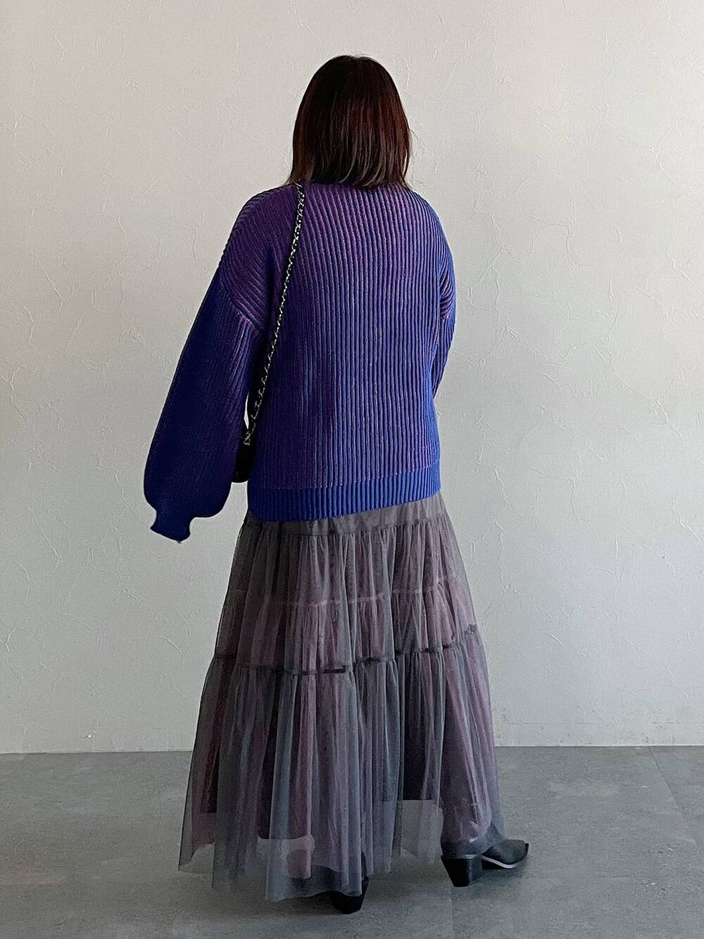 ブラック系のショルダーバッグ、グレー系のスカート、ブルー系のニット/セーターを着用したレディースの冬コーディネートの2枚目の写真