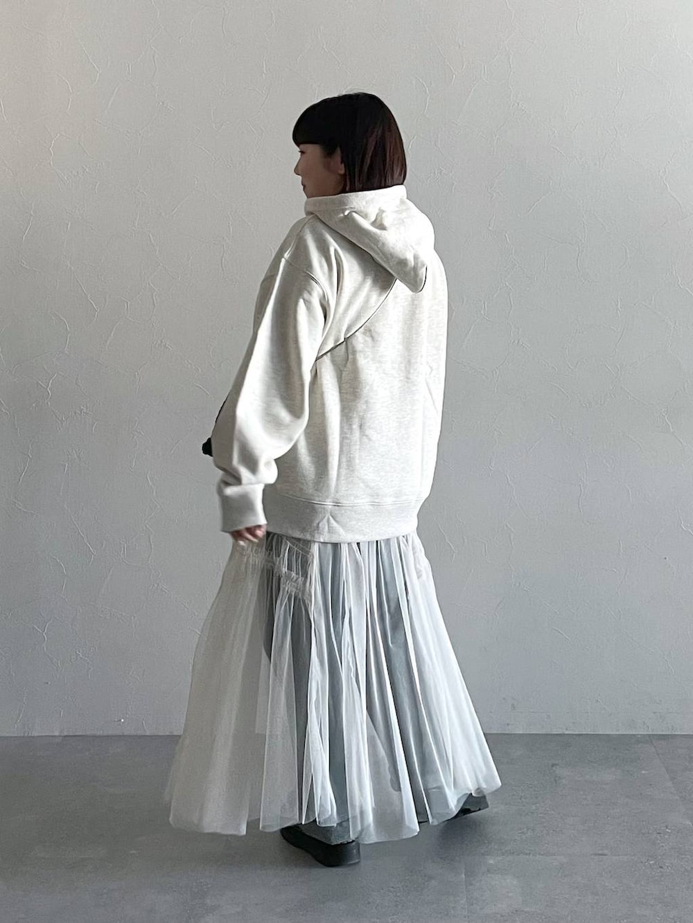 ブルー系のデニムパンツ、ホワイト系のスカート、ブラック系のショルダーバッグを着用したレディースの秋コーディネートの3枚目の写真