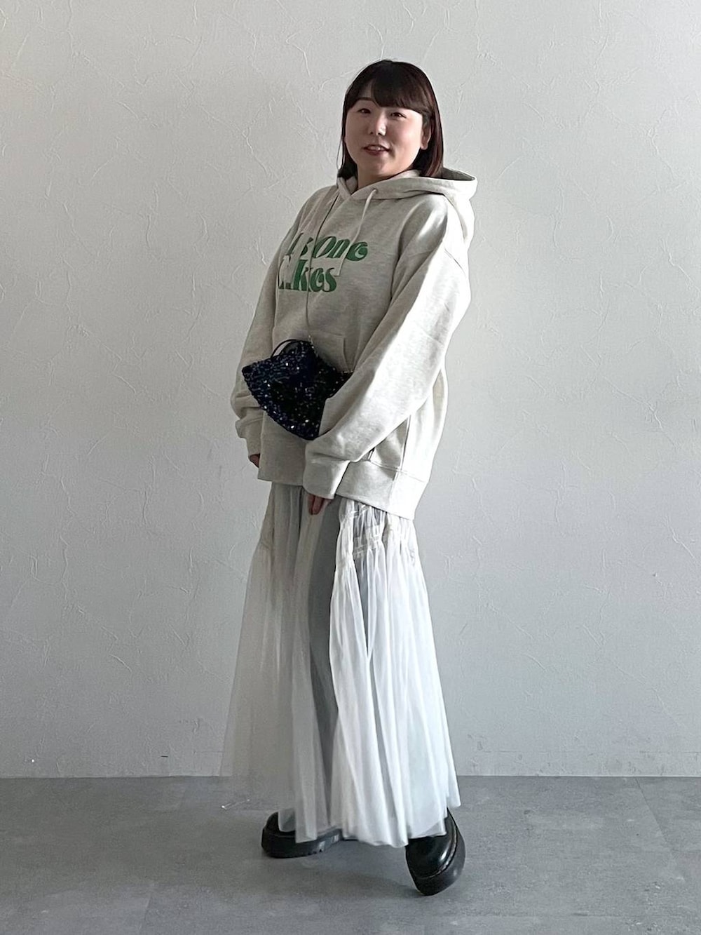 ブルー系のデニムパンツ、ホワイト系のスカート、ブラック系のショルダーバッグを着用したレディースの秋コーディネートの2枚目の写真