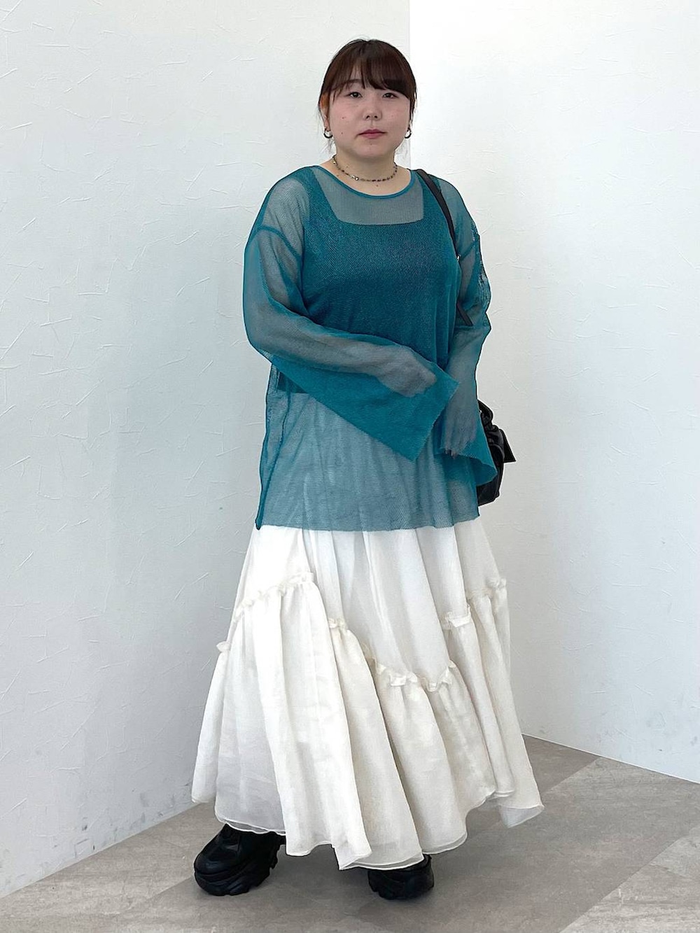 ブラック系のタンクトップ、ブラック系のショルダーバッグ、ホワイト系のスカートを着用したレディースの冬コーディネートの2枚目の写真