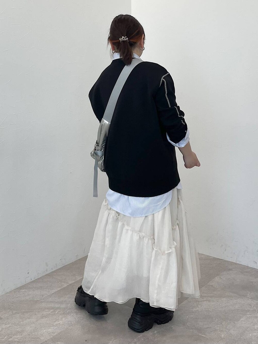 シルバー系のショルダーバッグ、ブルー系のシャツ/ブラウス、ブラック系のニット/セーターを着用したレディースの冬コーディネートの3枚目の写真