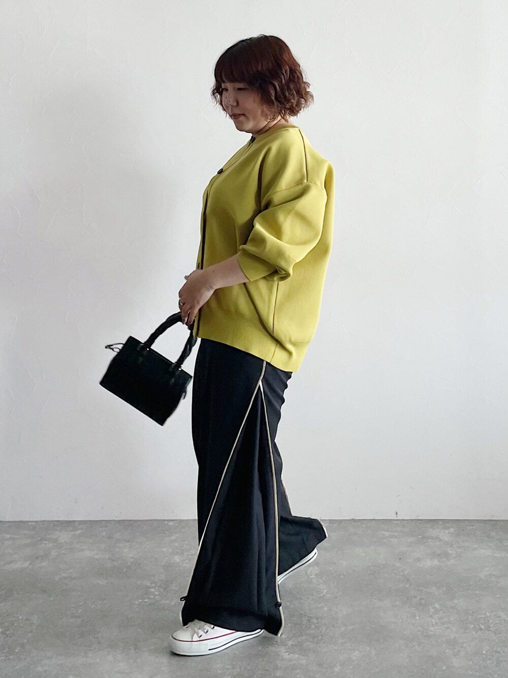 イエロー系のカーディガン/ボレロ、ブラック系のショルダーバッグ、ブラック系のスラックスを着用したレディースの夏コーディネートの2枚目の写真