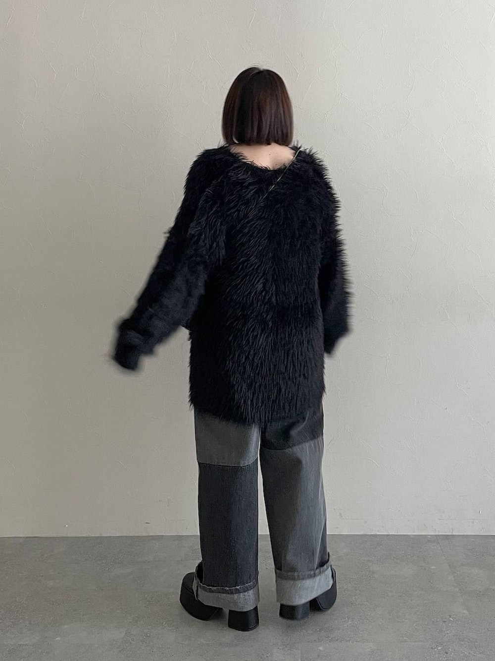 ブラック系のデニムパンツ、ブラック系のカーディガン/ボレロ、ブラック系のブーツを着用したレディースの秋コーディネートの2枚目の写真