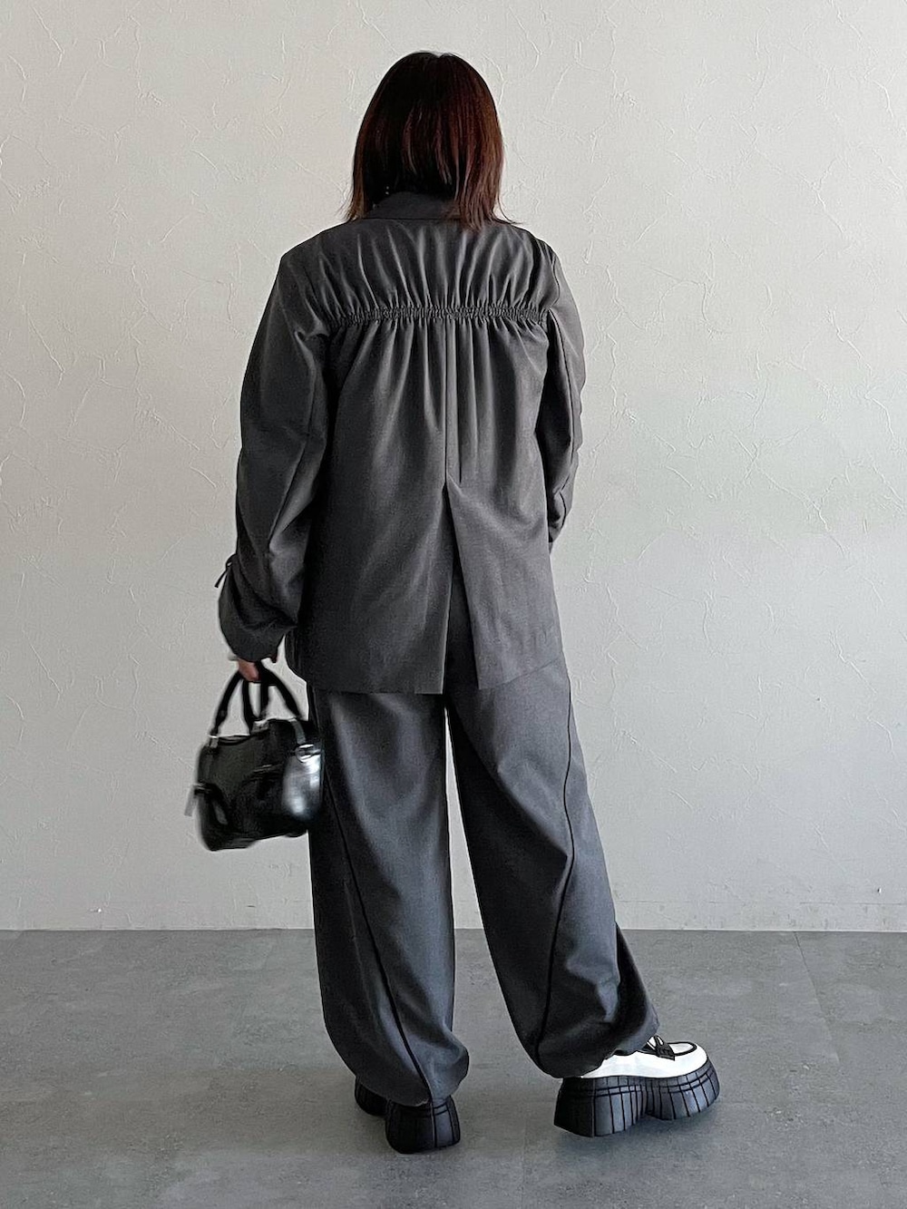 グレー系のその他パンツ、グレー系のテーラードジャケット、ホワイト系のローファーを着用したレディースの冬コーディネートの2枚目の写真
