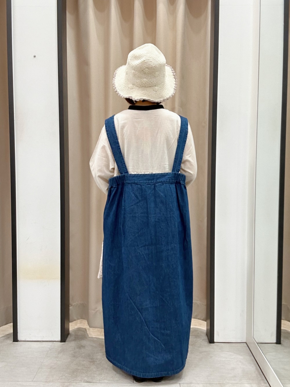 ホワイト系のハンドバッグ、ブラック系のドレスシューズ、ホワイト系のチュニックを着用したレディースの春コーディネートの2枚目の写真