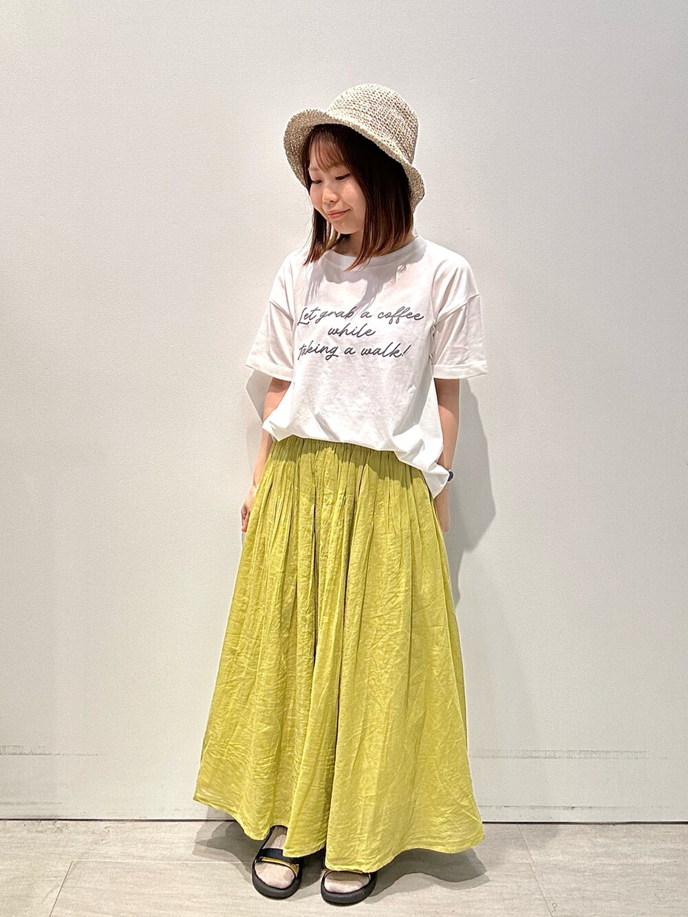 ホワイト系のTシャツ/カットソー、イエロー系のスカート、グレー系のハットを着用したレディースの夏コーディネートの2枚目の写真