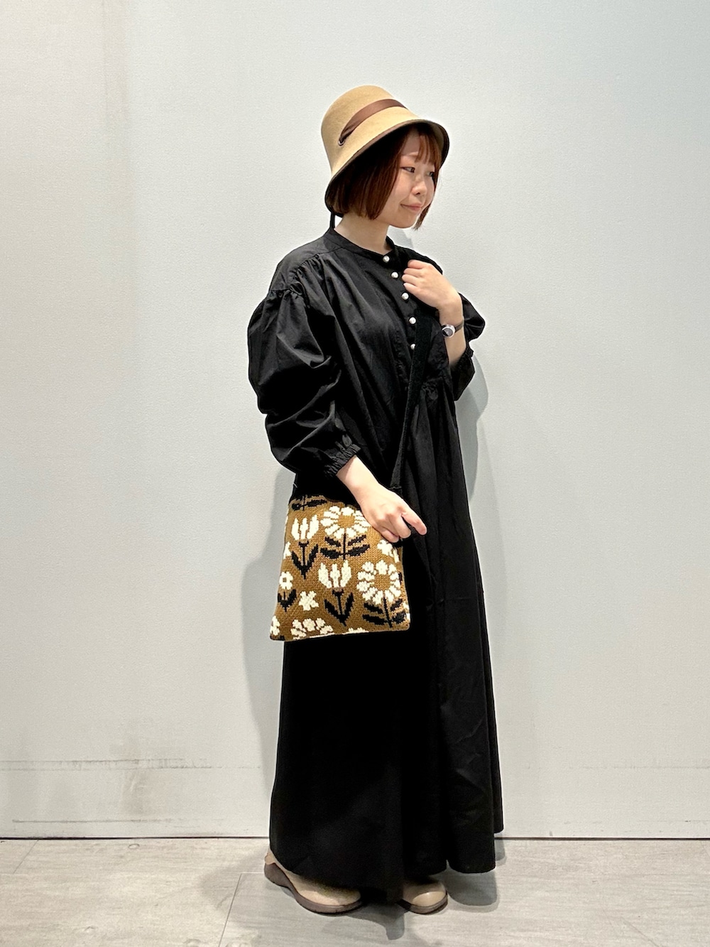 ブラック系のワンピース、イエロー系のハンドバッグ、イエロー系のハットを着用したレディースの秋コーディネートの2枚目の写真