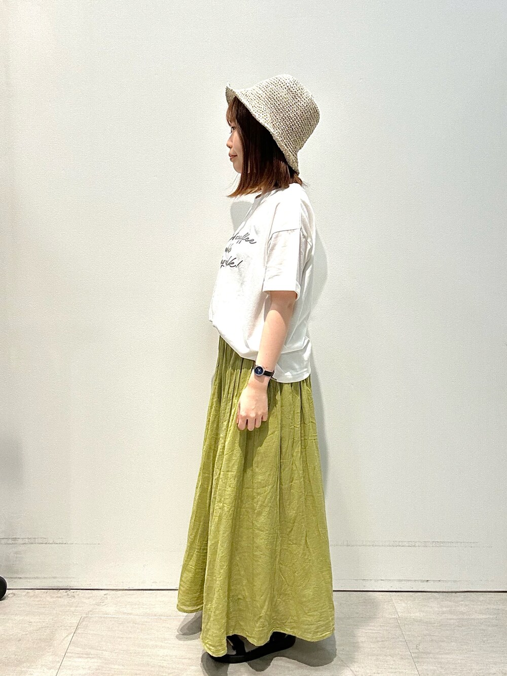 ホワイト系のTシャツ/カットソー、イエロー系のスカート、グレー系のハットを着用したレディースの夏コーディネートの3枚目の写真