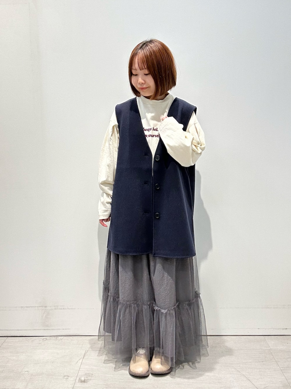 ホワイト系のTシャツ/カットソー、ブルー系のベスト、グレー系のスカートを着用したレディースの秋コーディネートの2枚目の写真