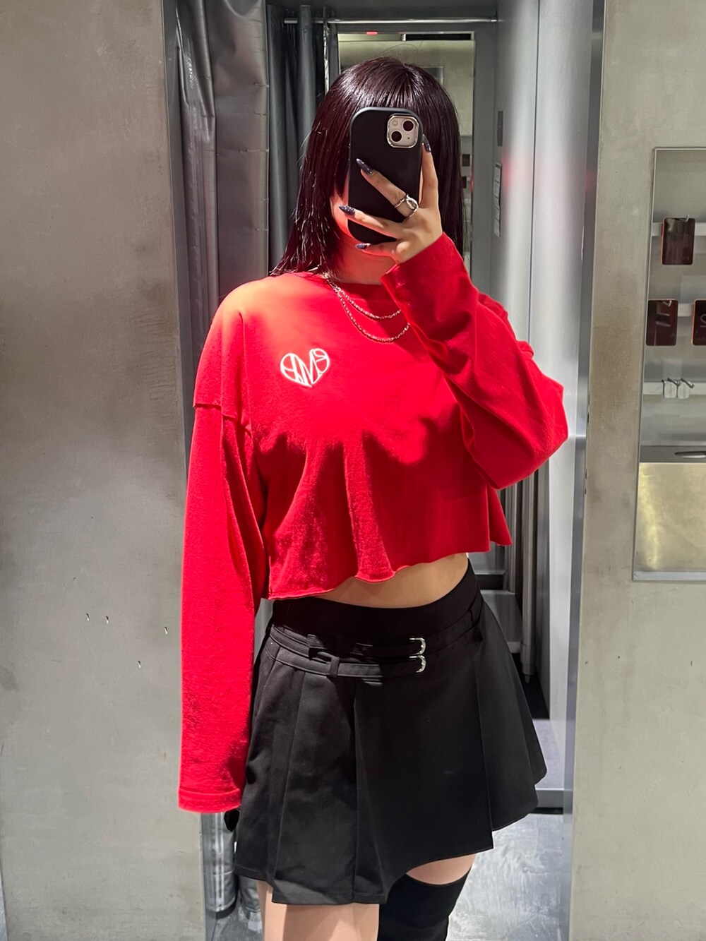 レッド系のTシャツ/カットソー、ブラック系のスカート、ブラック系のブーツを着用したレディースの秋コーディネートの4枚目の写真