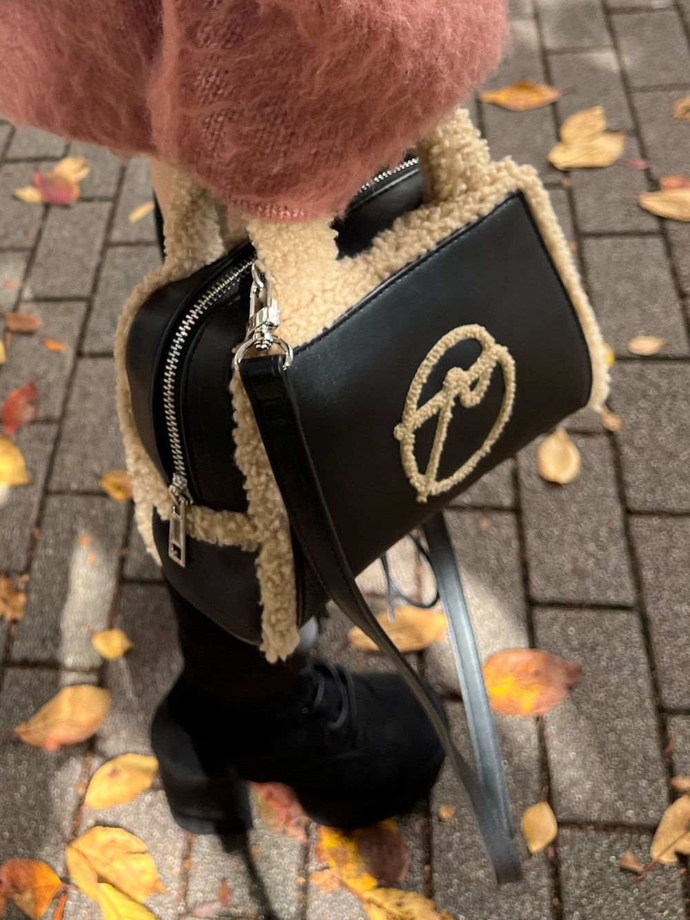 ピンク系のニット/セーター、ブラック系のスカート、ブラック系のハンドバッグを着用したレディースの冬コーディネートの6枚目の写真