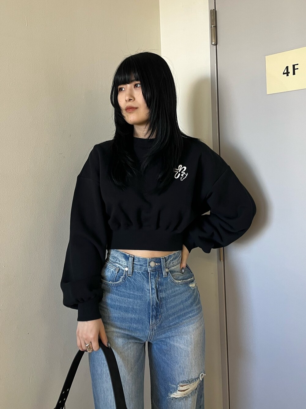 ブラック系のスウェット、ブルー系のデニムパンツ、ブラック系のショルダーバッグを着用したレディースの冬コーディネートの5枚目の写真