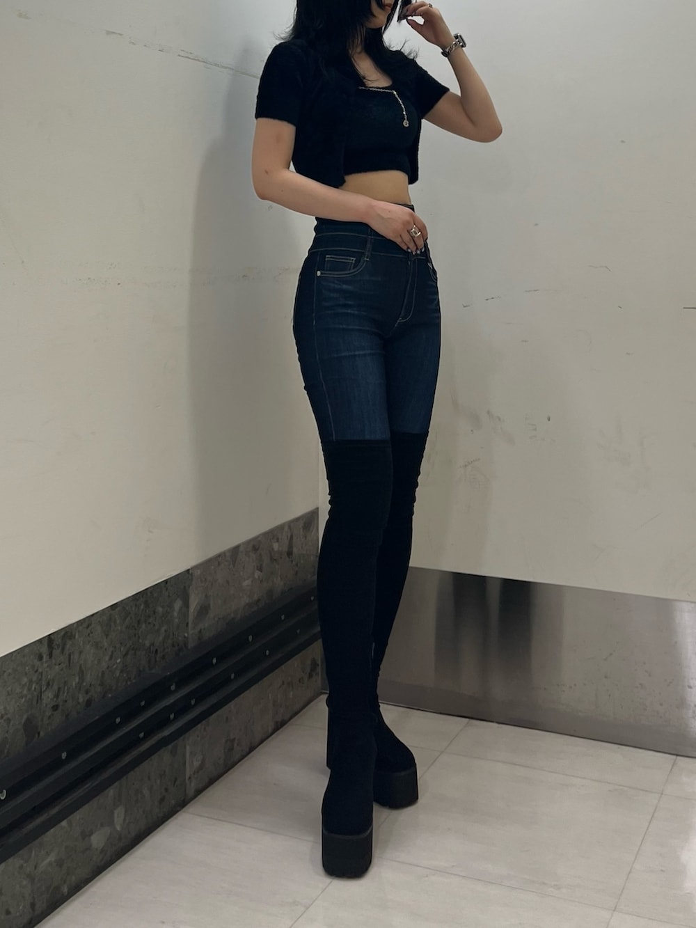 ブラック系のニット/セーター、ブルー系のデニムパンツ、ブラック系のブーツを着用したレディースの夏コーディネートの2枚目の写真