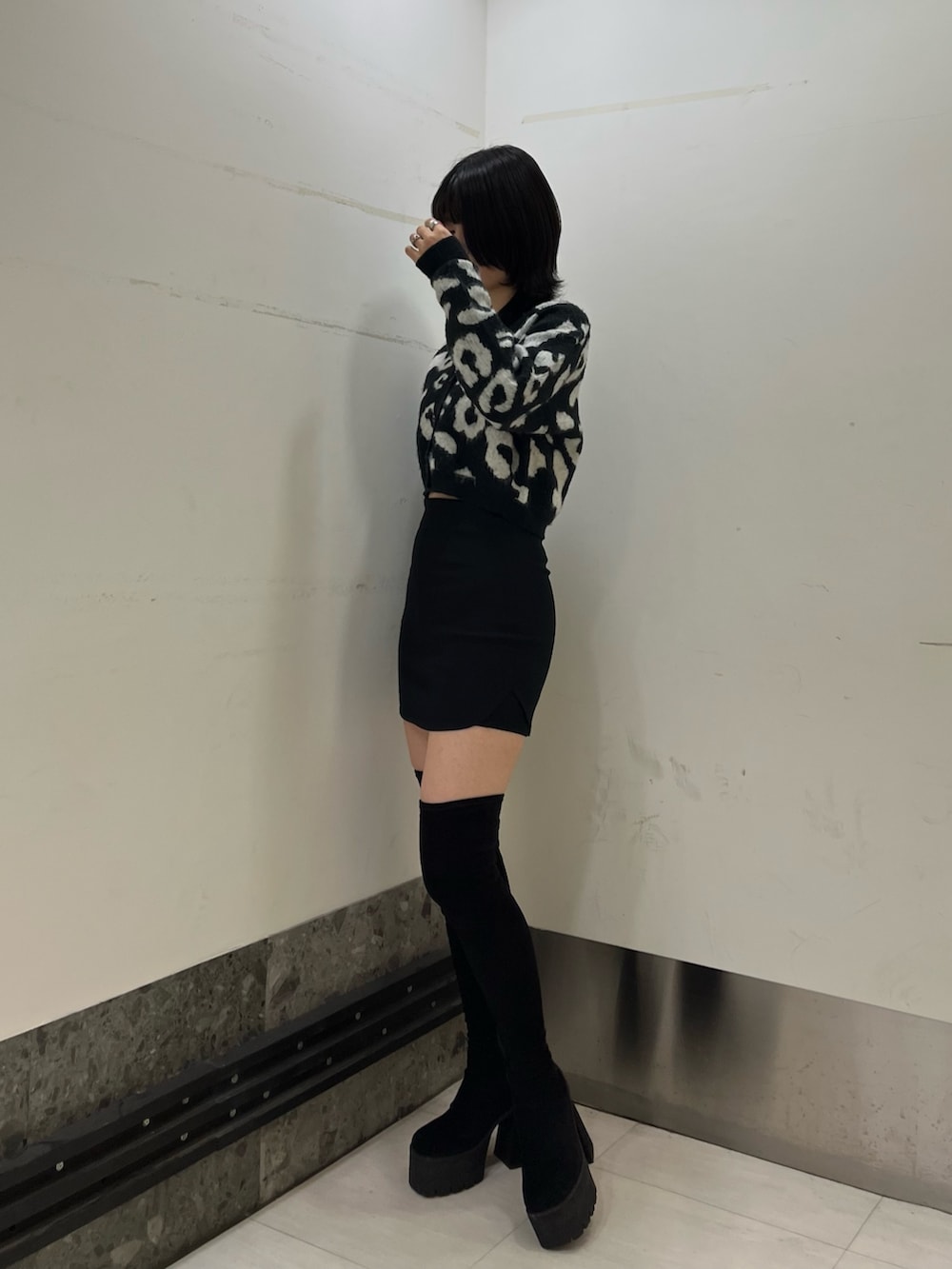 ブラック系のカーディガン/ボレロ、ブラック系のスカート、ブラック系のブーツを着用したレディースの冬コーディネートの2枚目の写真