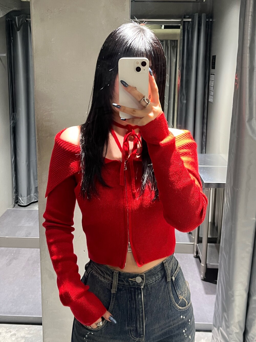 レッド系のニット/セーター、ブルー系のデニムパンツ、ブラック系のブーツを着用したレディースの秋コーディネートの4枚目の写真