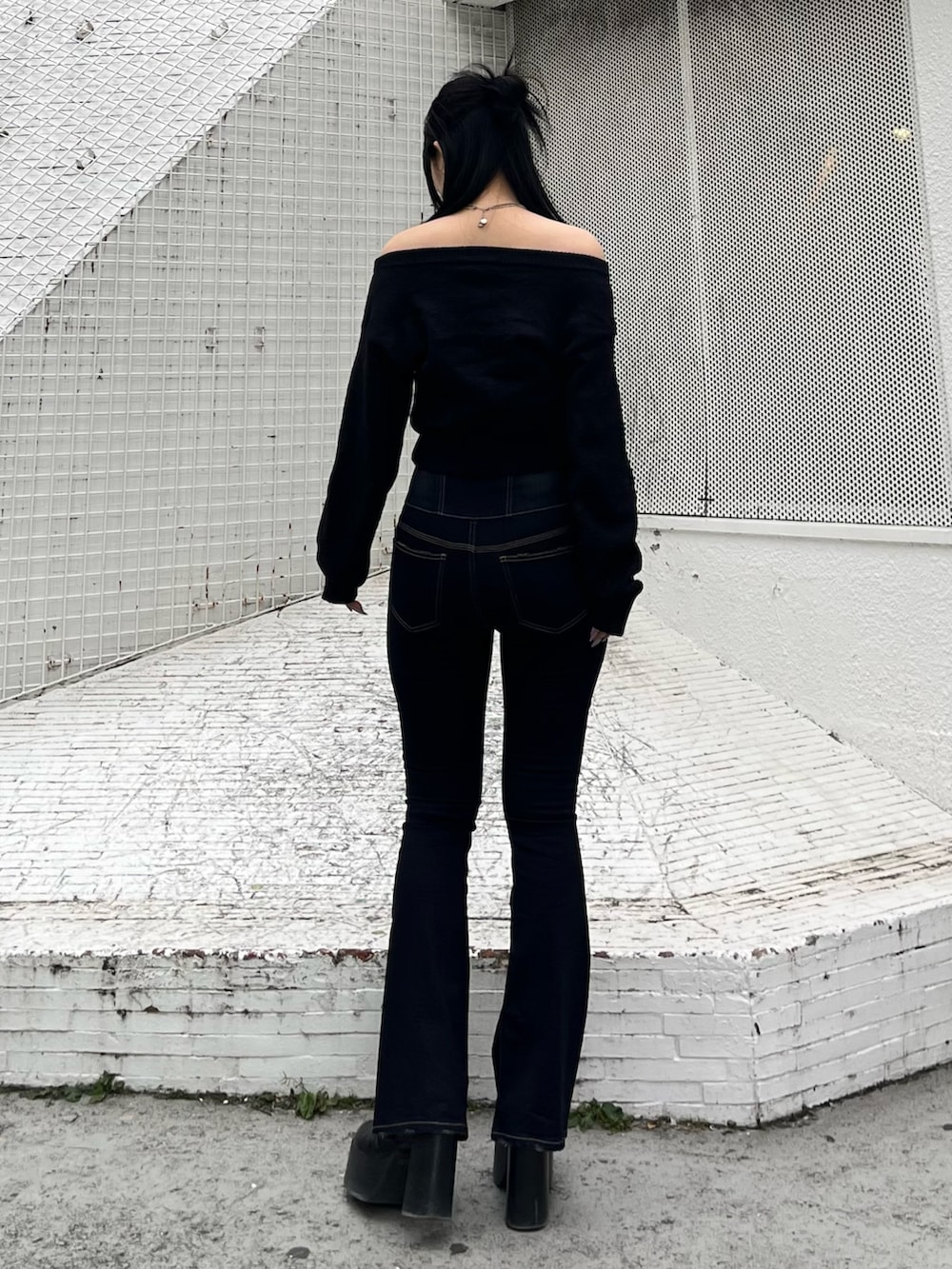 ブラック系のニット/セーター、ブルー系のデニムパンツ、ブラック系のブーツを着用したレディースの冬コーディネートの3枚目の写真