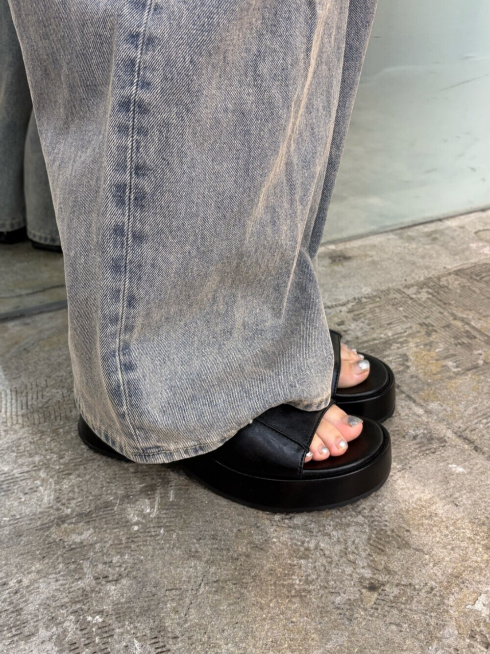 ブルー系のデニムパンツ、ブラック系のTシャツ/カットソー、ブラック系のサンダルを着用したレディースの夏コーディネートの6枚目の写真