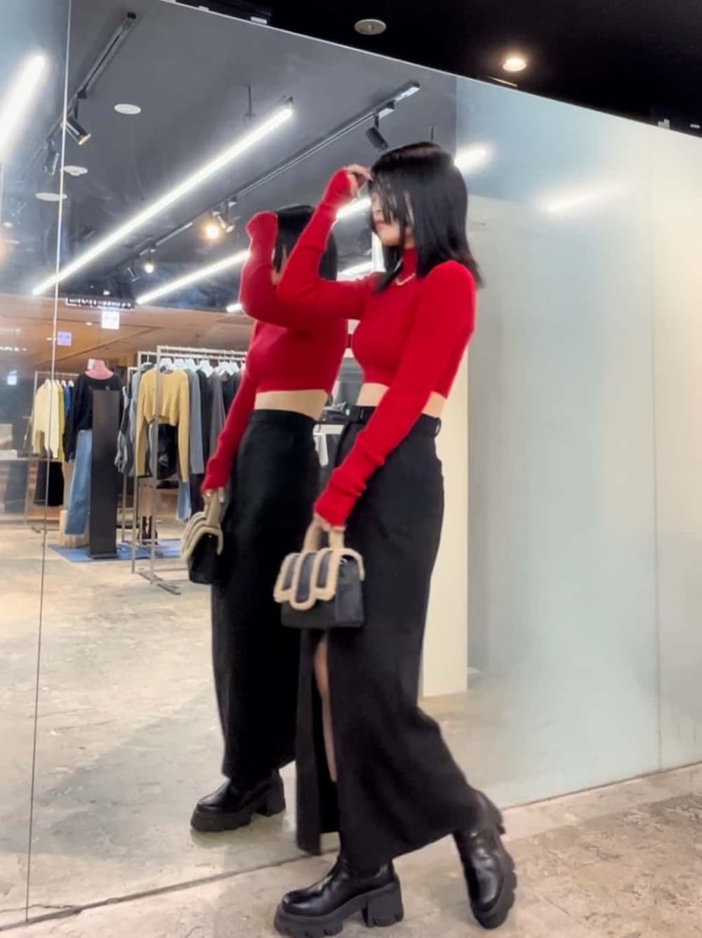 ブラック系のブーツ、レッド系のニット/セーター、ブラック系のスカートを着用したレディースの秋コーディネートの3枚目の写真