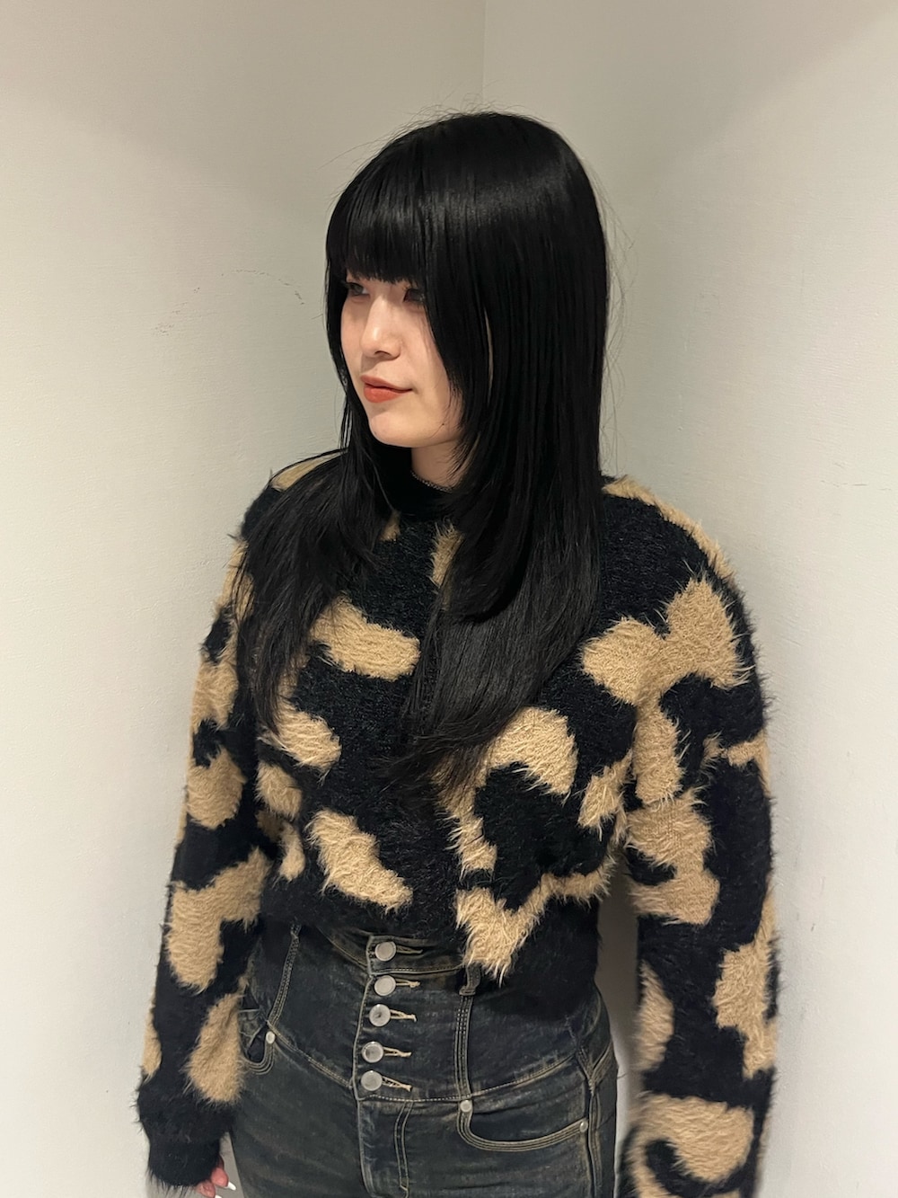 ブラック系のニット/セーター、ブルー系のデニムパンツ、ブラック系のブーツを着用したレディースの冬コーディネートの4枚目の写真