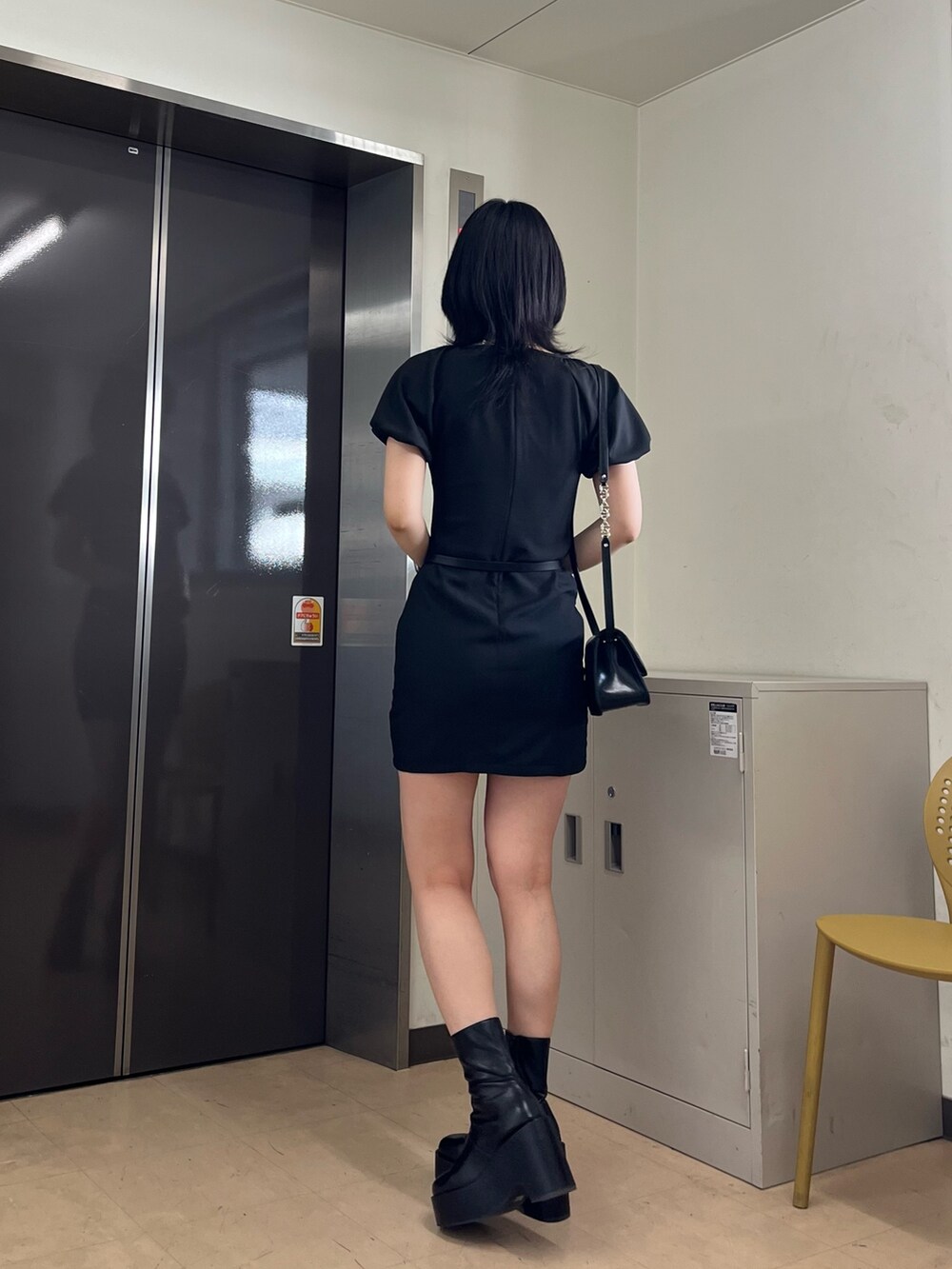 ブラック系のワンピース、ブラック系のショルダーバッグ、ブラック系のブーツを着用したレディースの春コーディネートの4枚目の写真