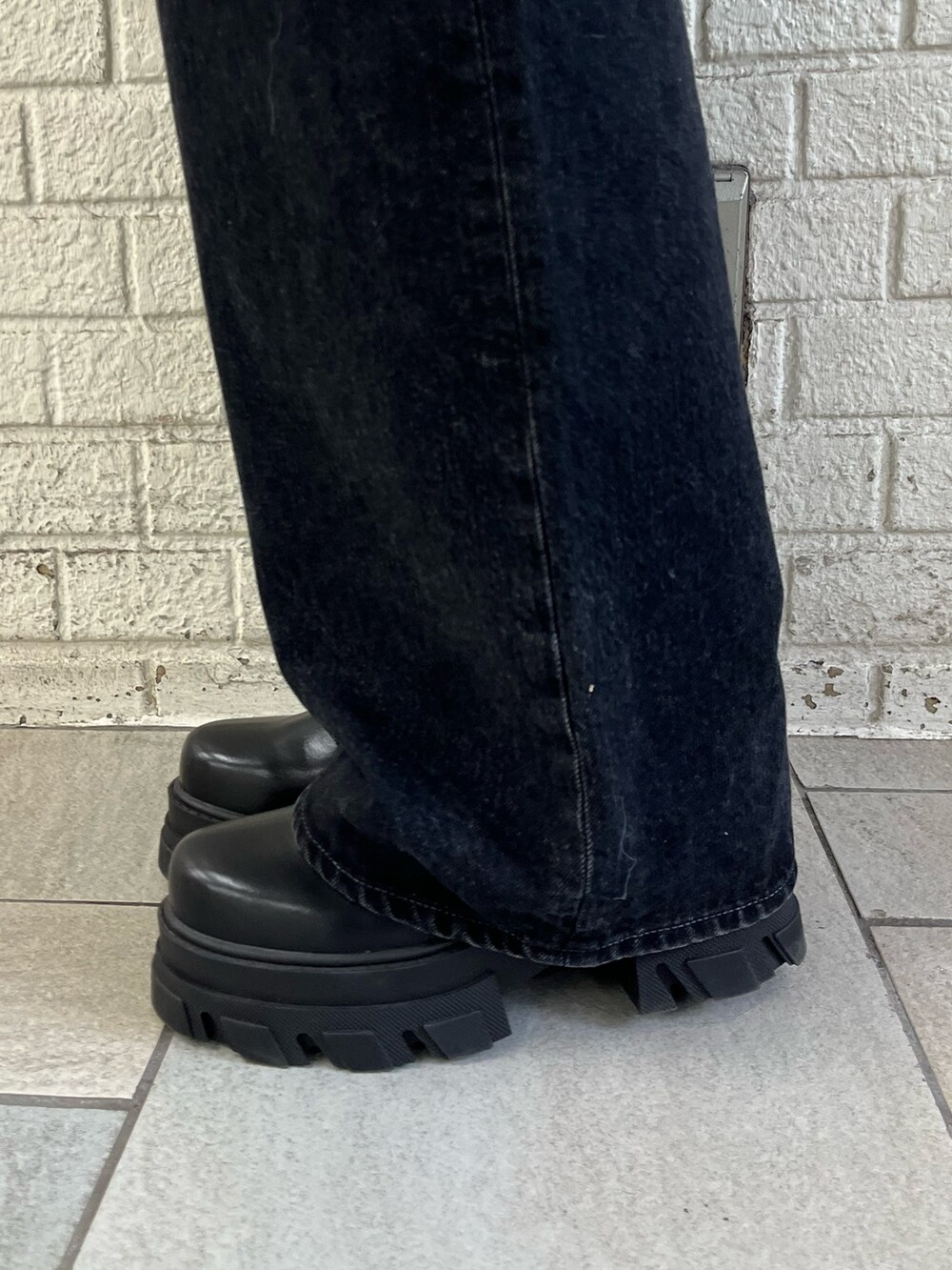 ブラック系のニット/セーター、ブラック系のデニムパンツ、ブラック系のブーツを着用したレディースの冬コーディネートの6枚目の写真