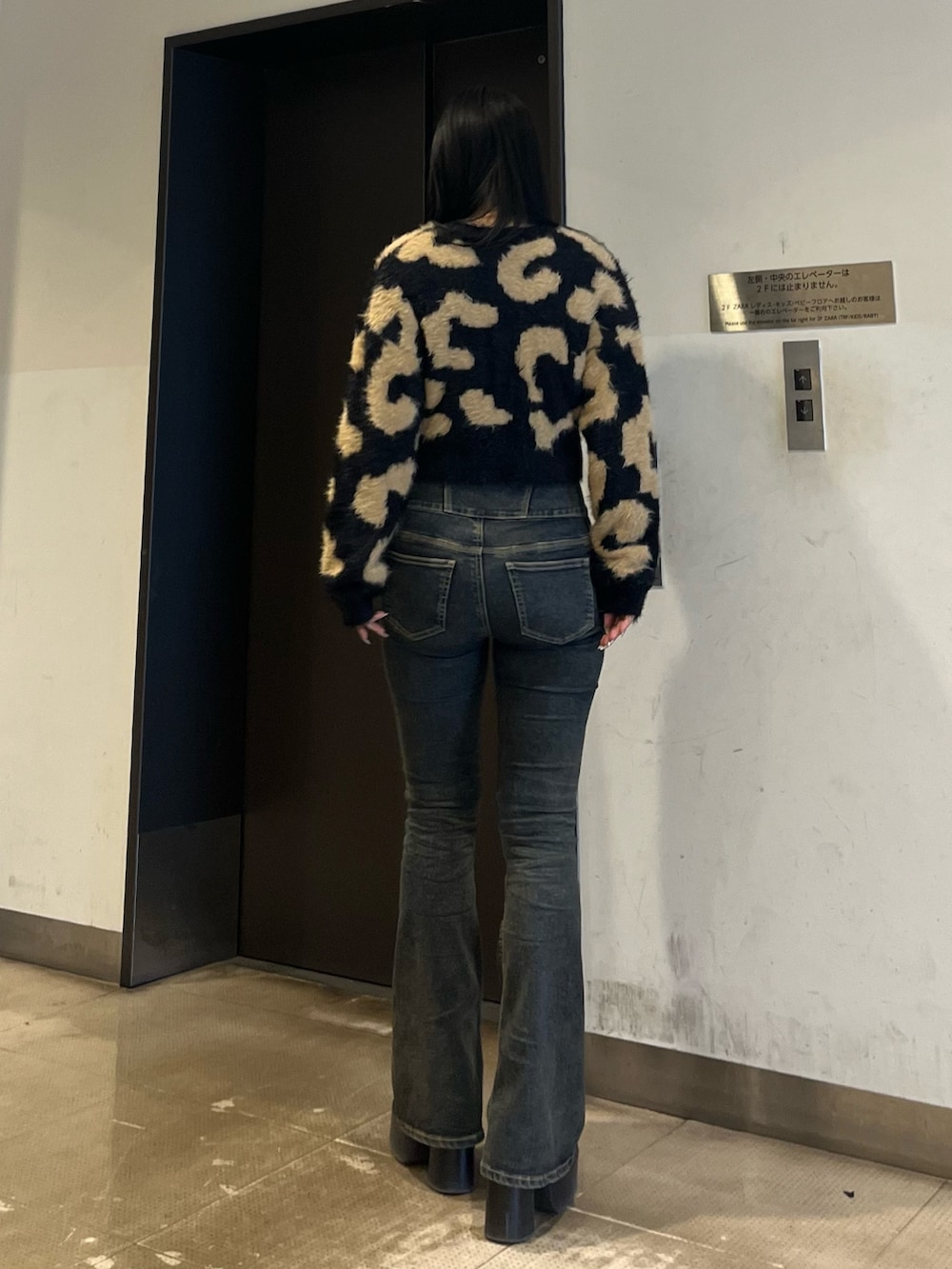 ブラック系のニット/セーター、ブルー系のデニムパンツ、ブラック系のブーツを着用したレディースの冬コーディネートの3枚目の写真