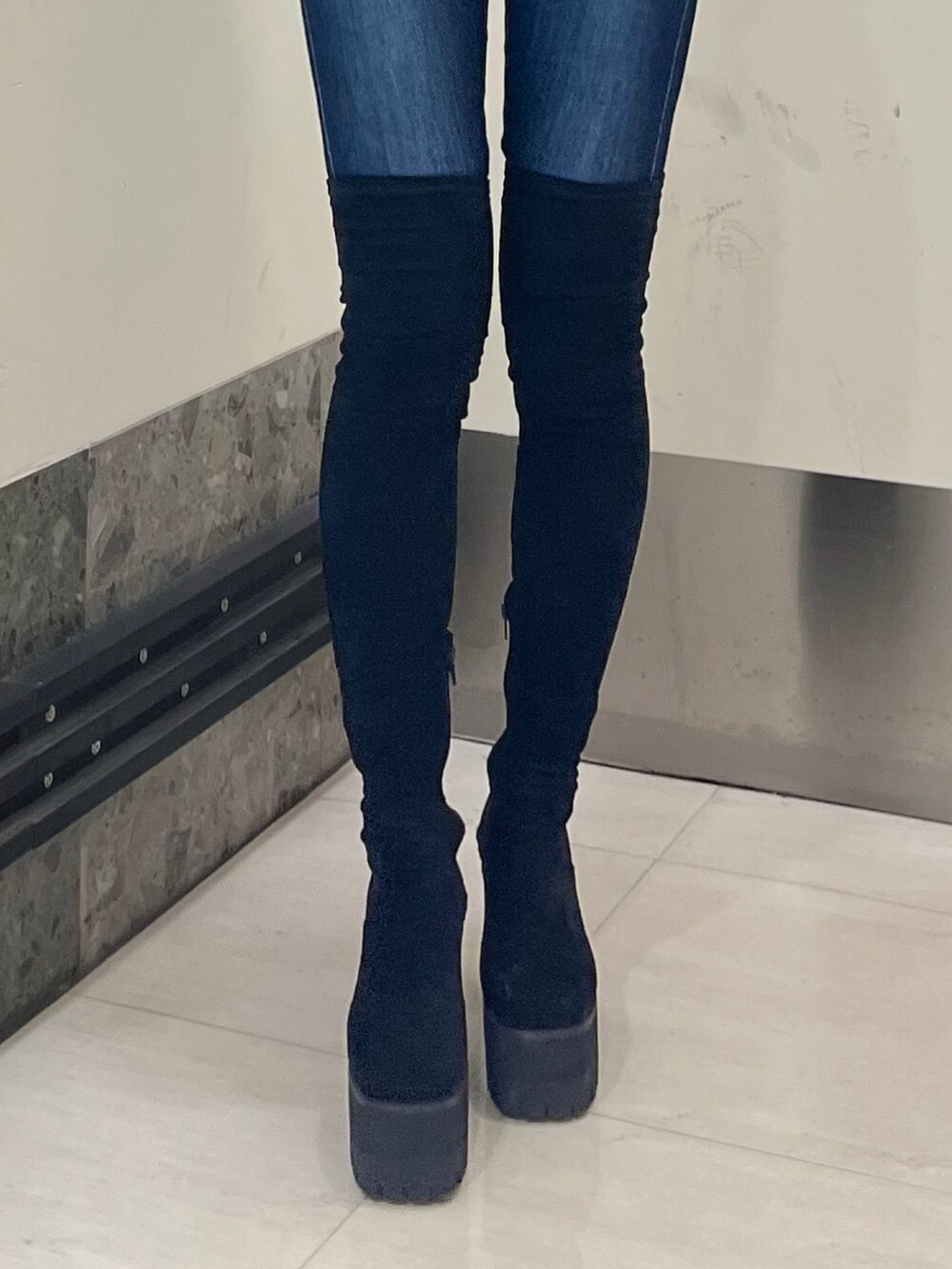 ブラック系のニット/セーター、ブルー系のデニムパンツ、ブラック系のブーツを着用したレディースの夏コーディネートの6枚目の写真