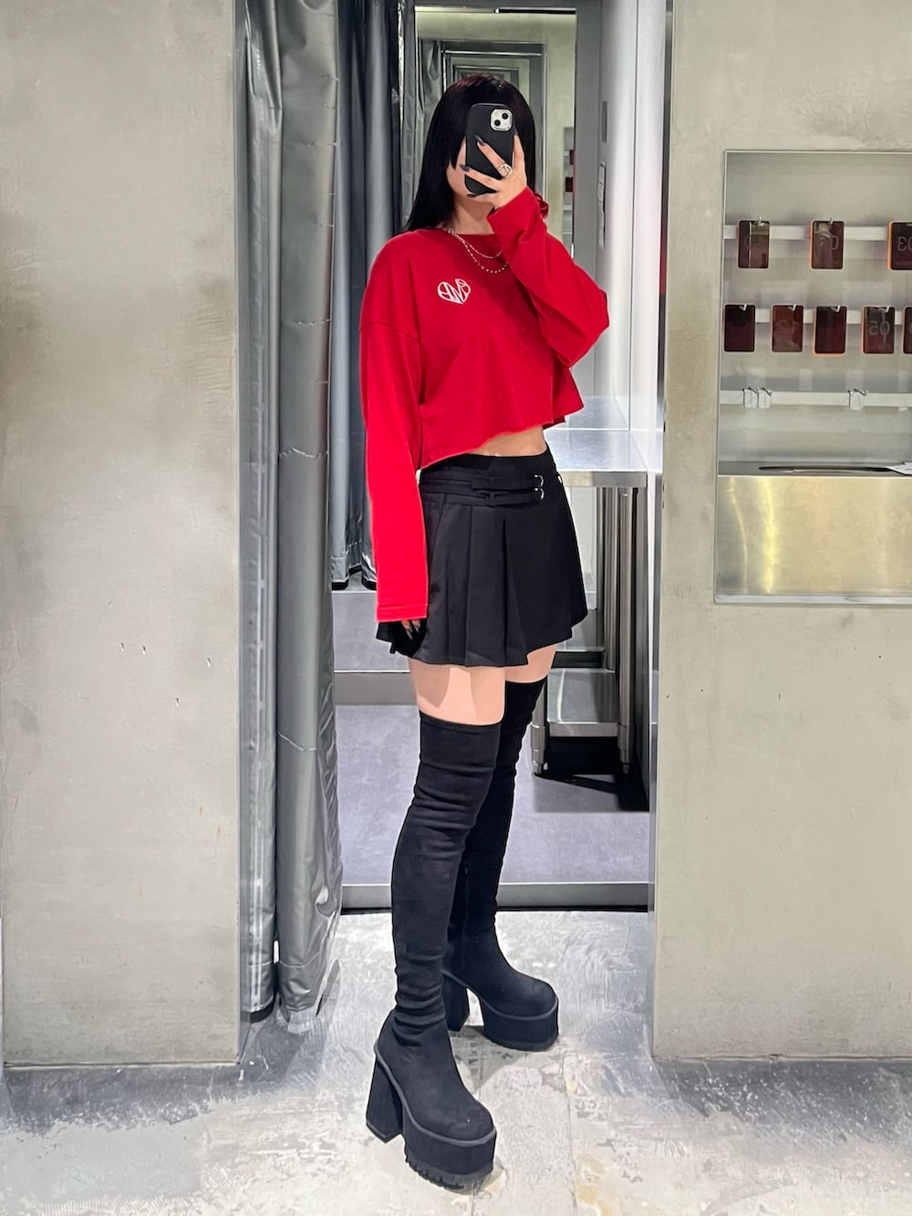 レッド系のTシャツ/カットソー、ブラック系のスカート、ブラック系のブーツを着用したレディースの秋コーディネートの2枚目の写真