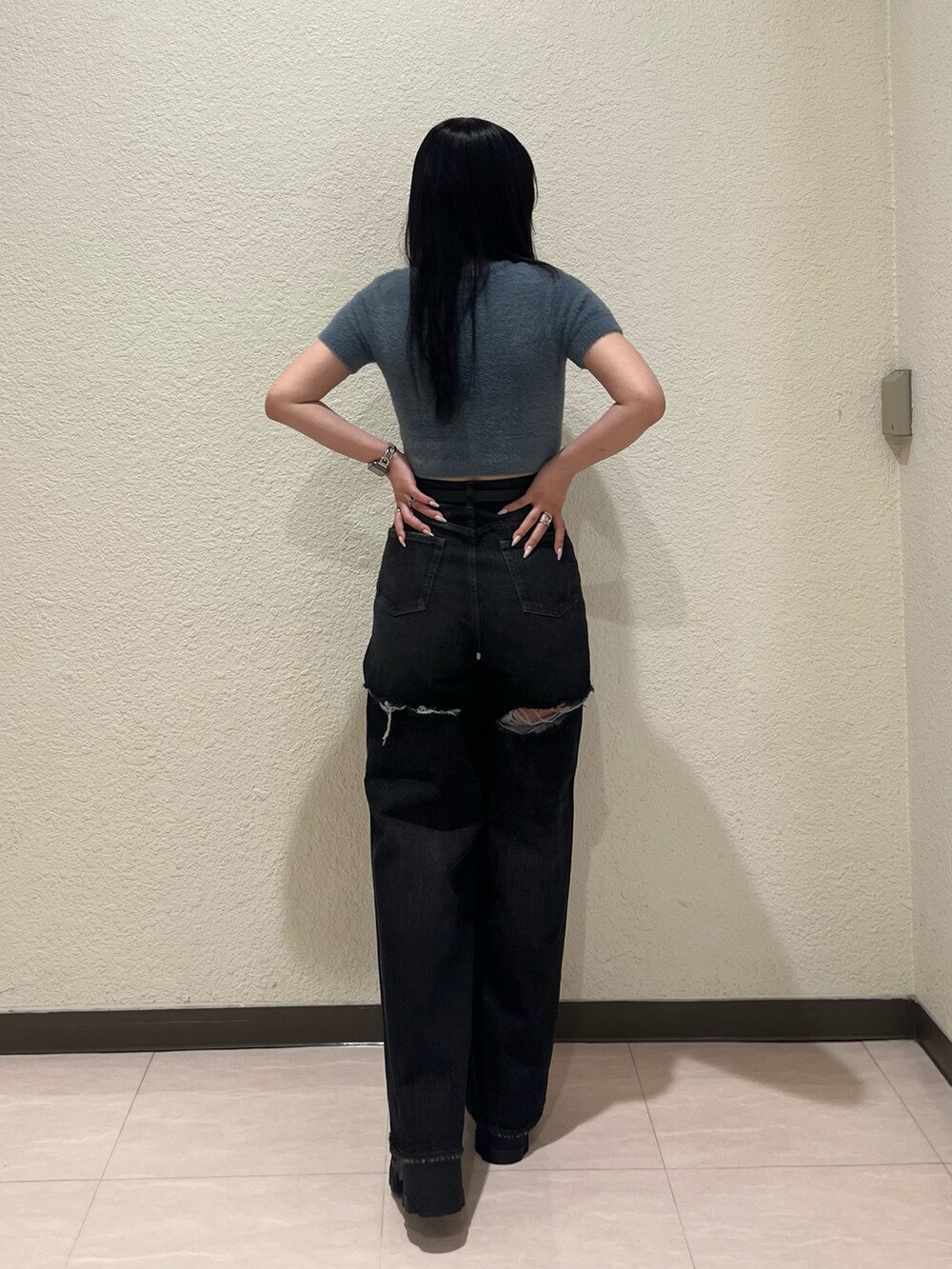 ブルー系のニット/セーター、ブラック系のデニムパンツ、ブラック系のブーツを着用したレディースの夏コーディネートの3枚目の写真
