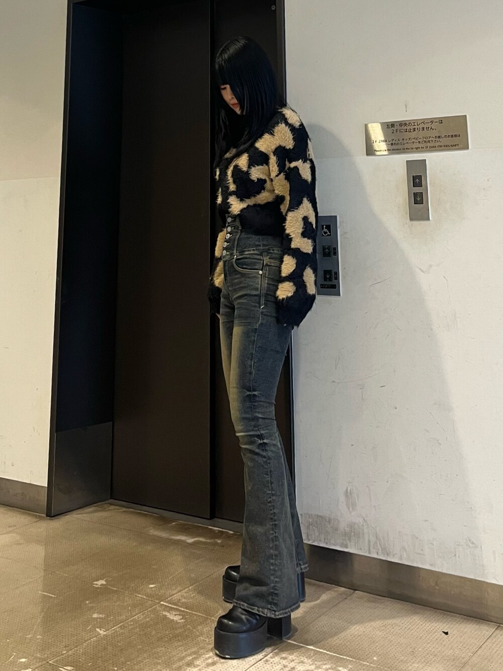 ブラック系のニット/セーター、ブルー系のデニムパンツ、ブラック系のブーツを着用したレディースの冬コーディネートの2枚目の写真