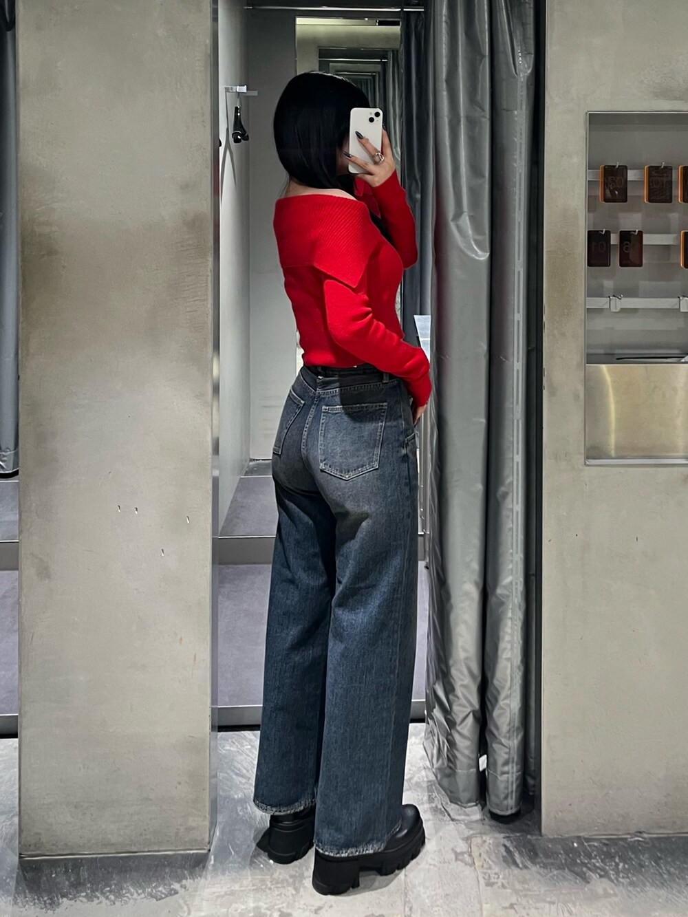 レッド系のニット/セーター、ブルー系のデニムパンツ、ブラック系のブーツを着用したレディースの秋コーディネートの3枚目の写真