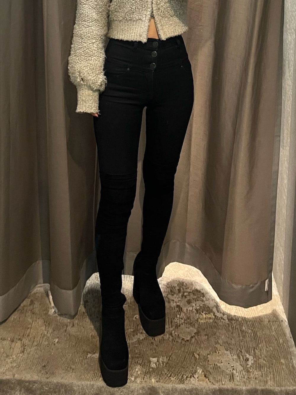 グレー系のニット/セーター、ブラック系のデニムパンツ、ブラック系のブーツを着用したレディースの秋コーディネートの5枚目の写真