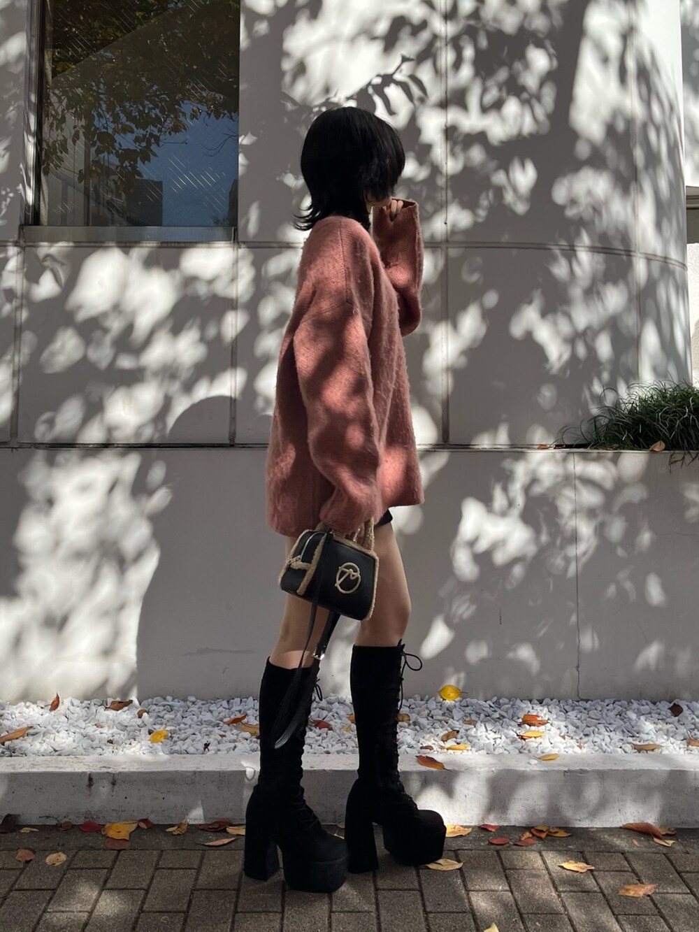 ピンク系のニット/セーター、ブラック系のスカート、ブラック系のハンドバッグを着用したレディースの冬コーディネートの2枚目の写真