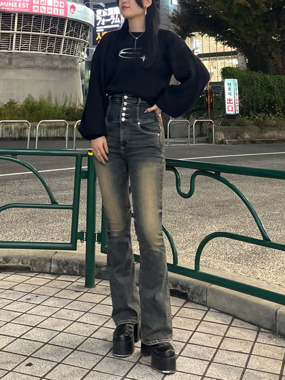 ブラック系のニット/セーター、ブルー系のデニムパンツ、ブラック系のブーツを着用したレディースの秋コーディネートの2枚目の写真