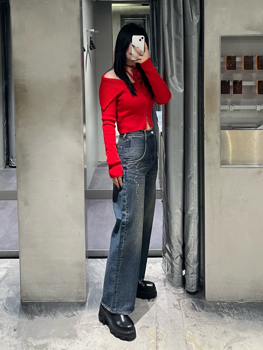 レッド系のニット/セーター、ブルー系のデニムパンツ、ブラック系のブーツを着用したレディースの秋コーディネートの2枚目の写真
