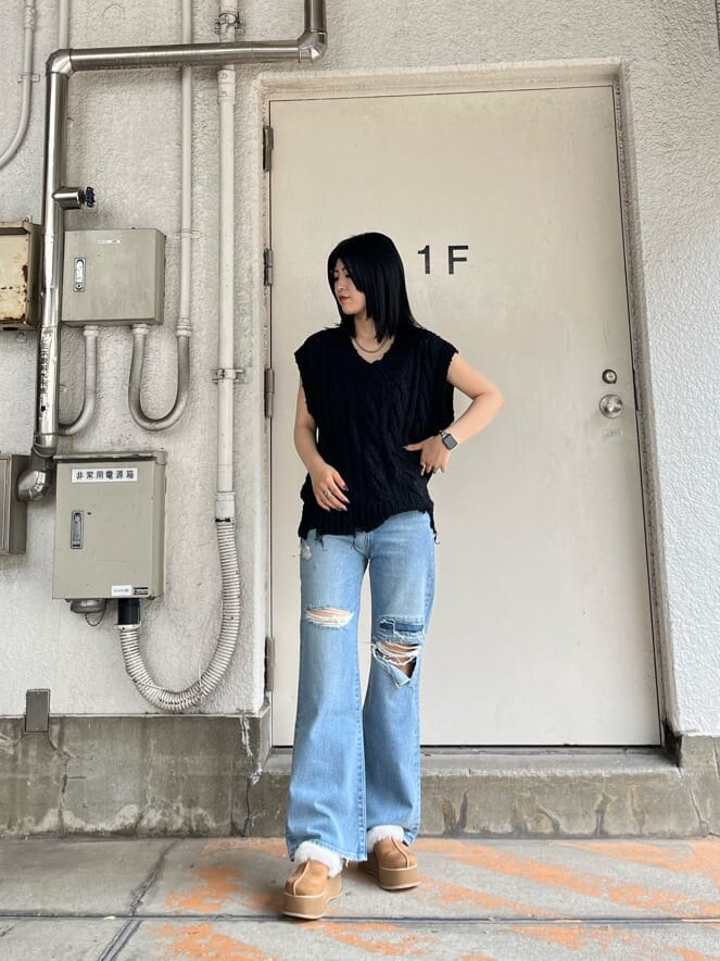 ブルー系のデニムパンツ、ベージュ系のスリッポン、ブラック系のベストを着用したレディースの秋コーディネートの2枚目の写真