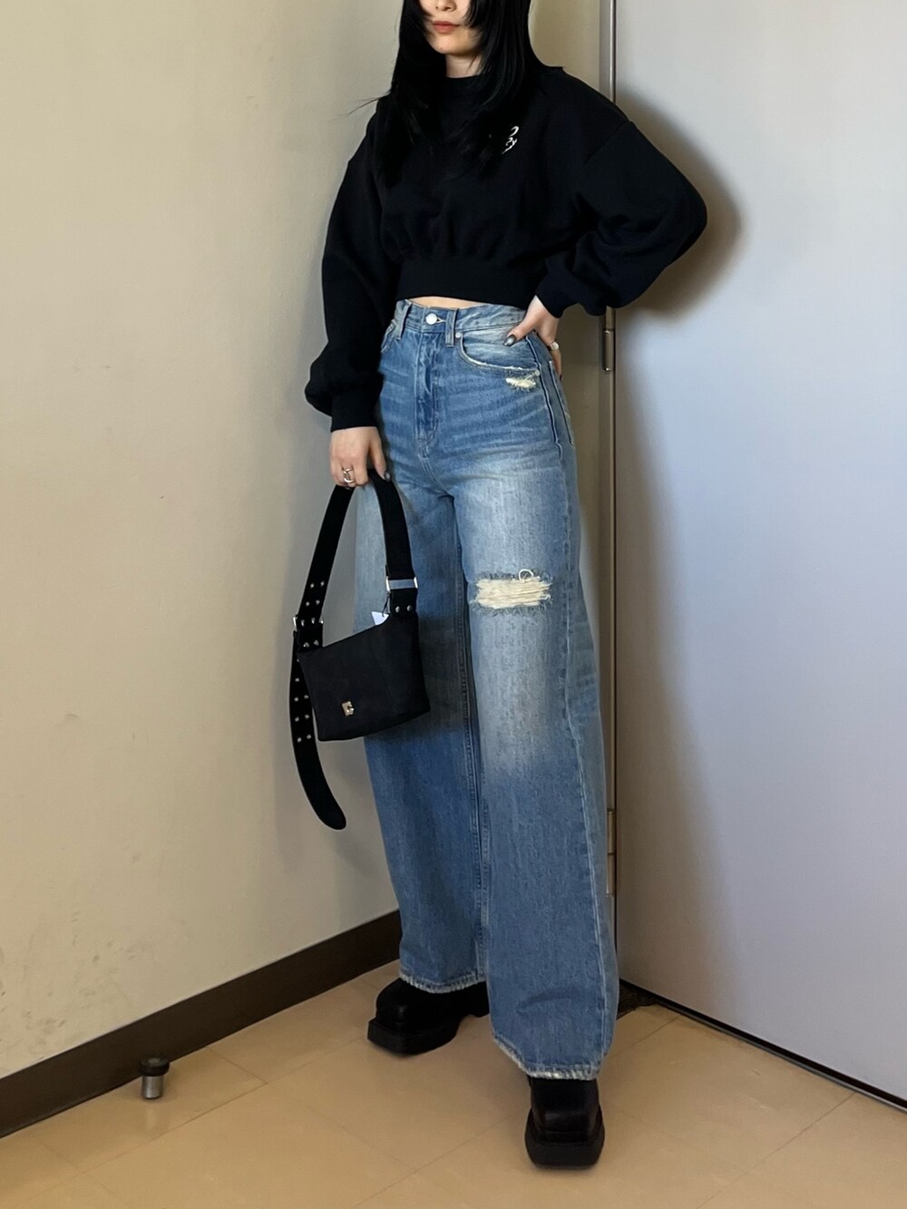 ブラック系のスウェット、ブルー系のデニムパンツ、ブラック系のショルダーバッグを着用したレディースの冬コーディネートの2枚目の写真