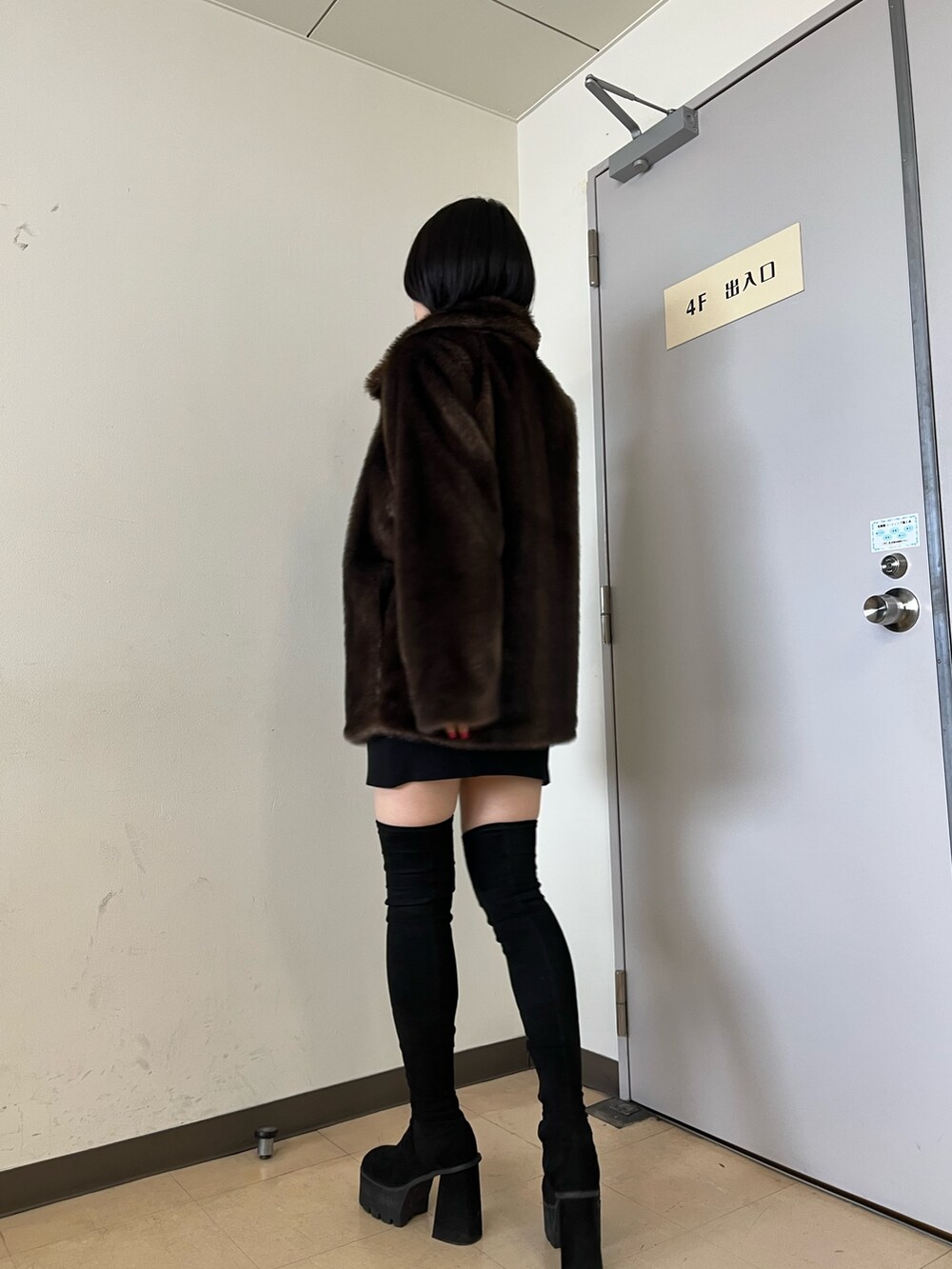 ブラウン系のその他アウター、ブラック系のワンピース、ブラック系のブーツを着用したレディースの冬コーディネートの2枚目の写真