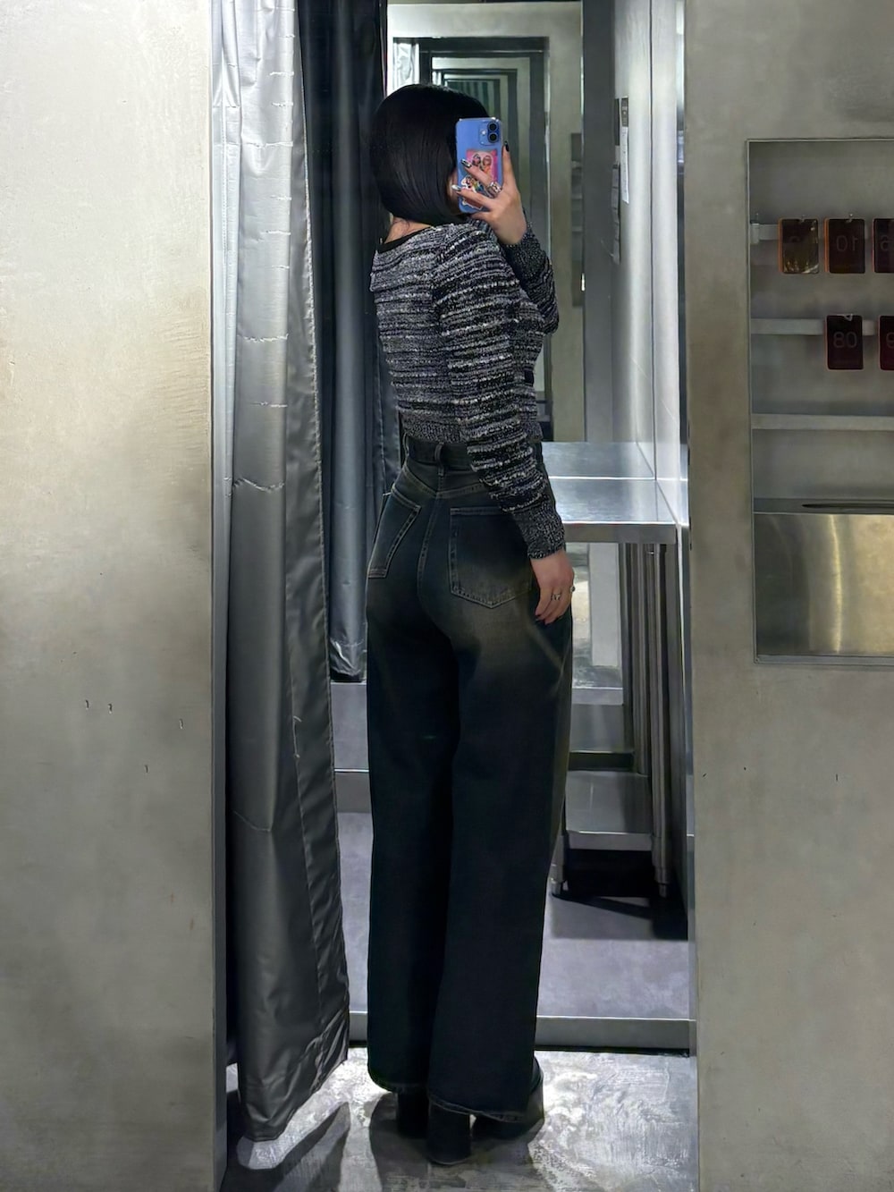 ブラック系のニット/セーター、ブルー系のデニムパンツ、ブラック系のブーツを着用したレディースの冬コーディネートの3枚目の写真