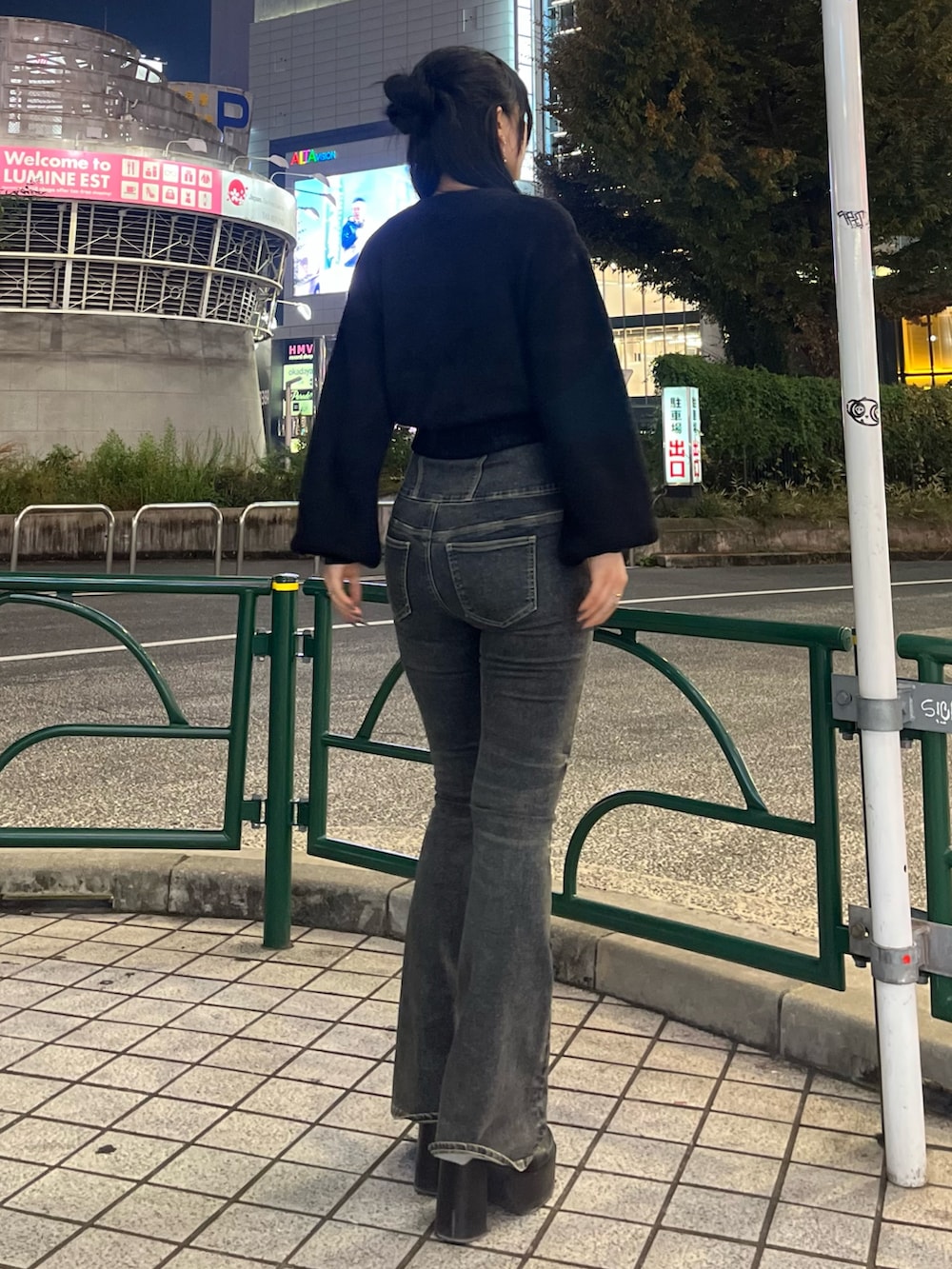 ブラック系のニット/セーター、ブルー系のデニムパンツ、ブラック系のブーツを着用したレディースの秋コーディネートの4枚目の写真