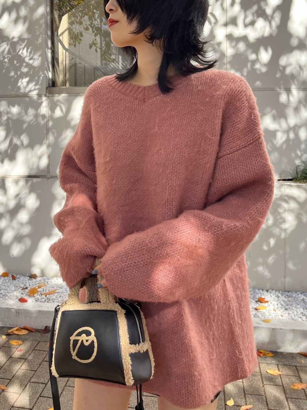 ピンク系のニット/セーター、ブラック系のスカート、ブラック系のハンドバッグを着用したレディースの冬コーディネートの5枚目の写真