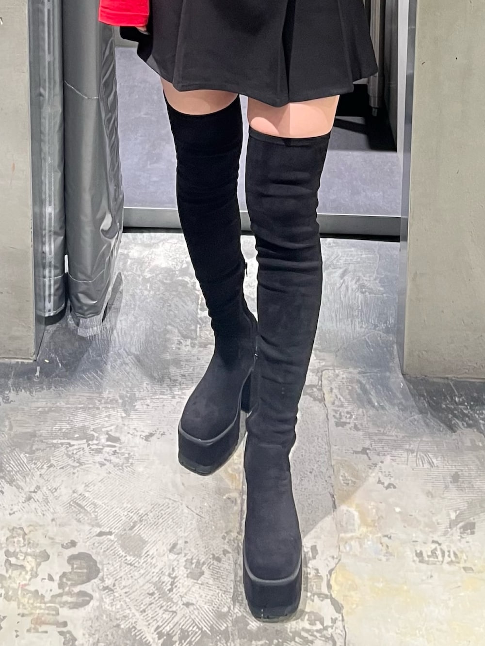 レッド系のTシャツ/カットソー、ブラック系のスカート、ブラック系のブーツを着用したレディースの秋コーディネートの6枚目の写真