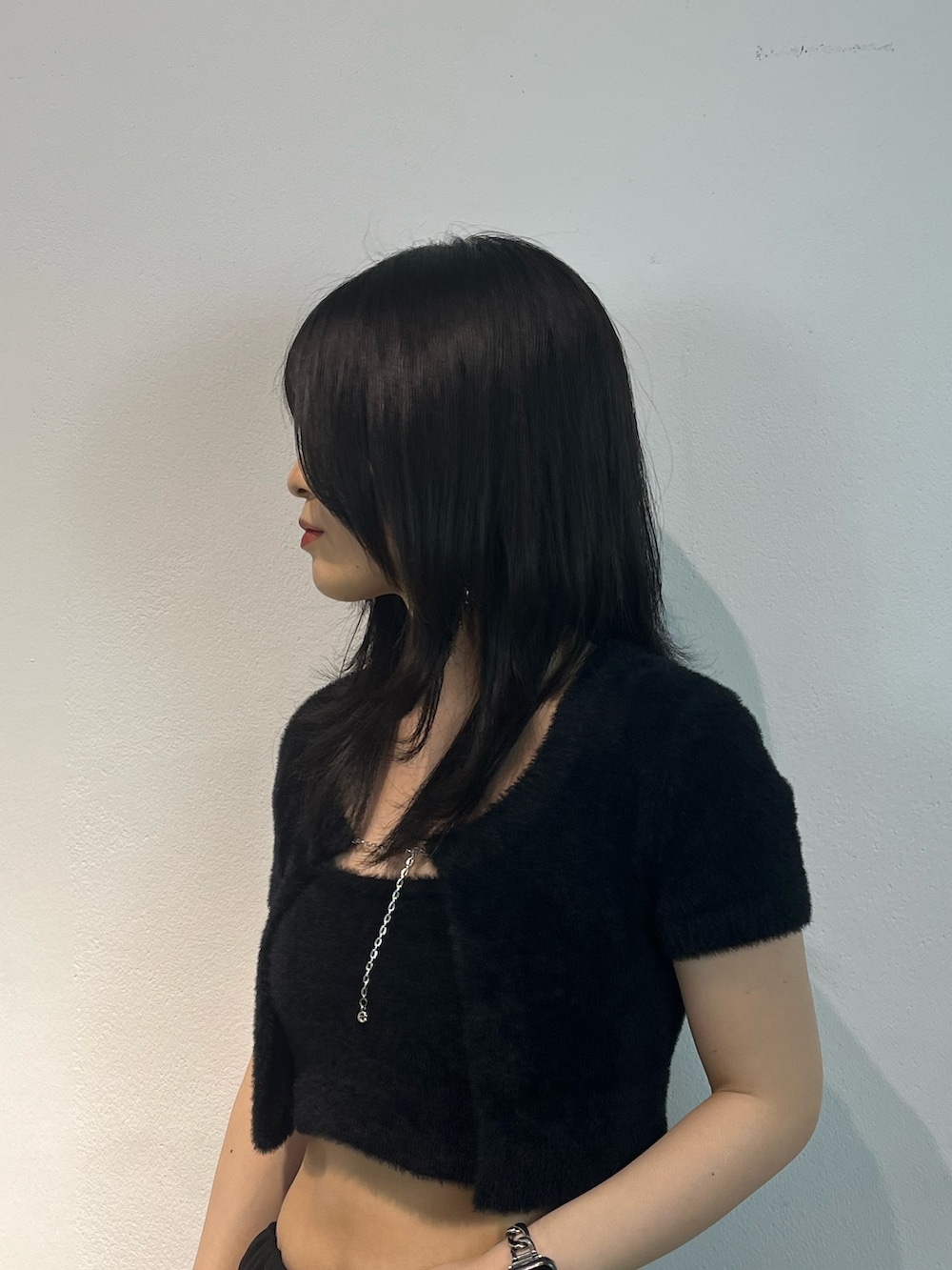 ブラック系のニット/セーター、ブルー系のデニムパンツ、ブラック系のブーツを着用したレディースの夏コーディネートの5枚目の写真